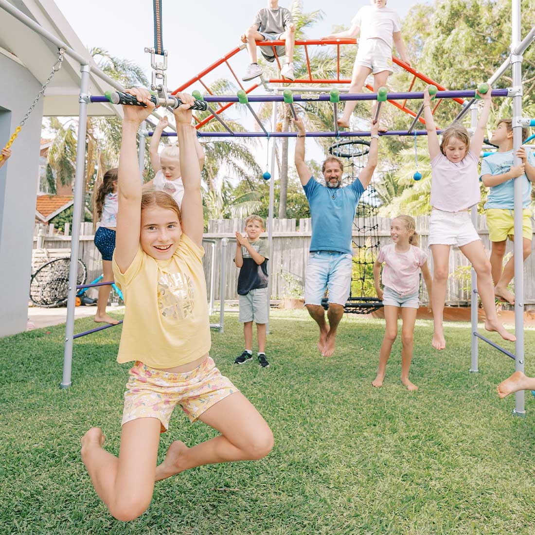 Family playing on Monkey Bars Frame while child swings on a flying fox